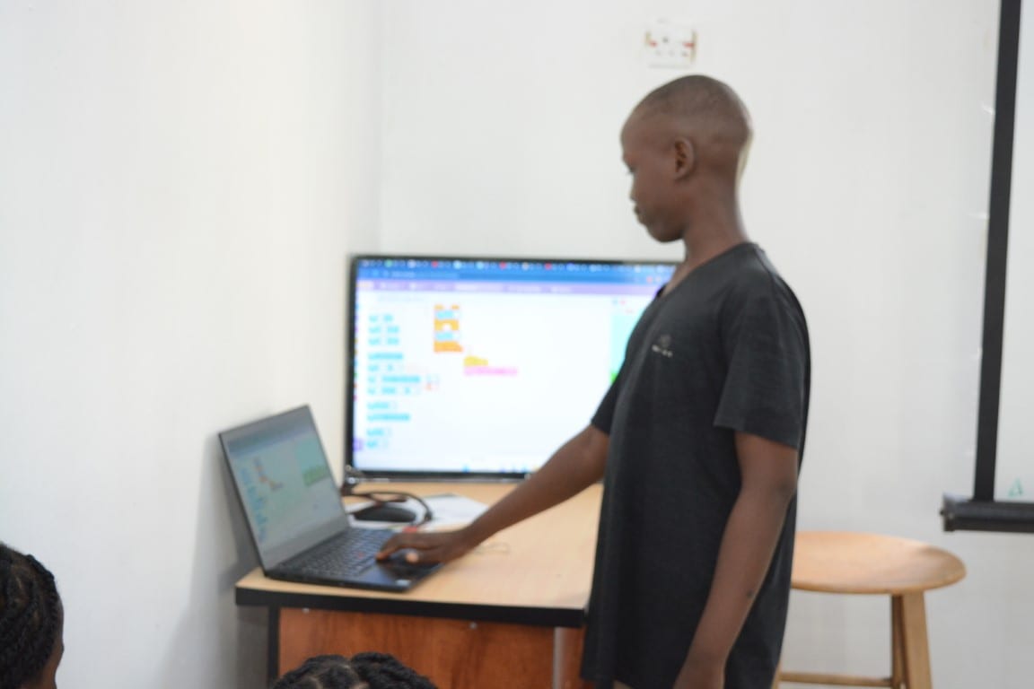 A child working through a Scratch project at a laptop in a Toko Academy coding class